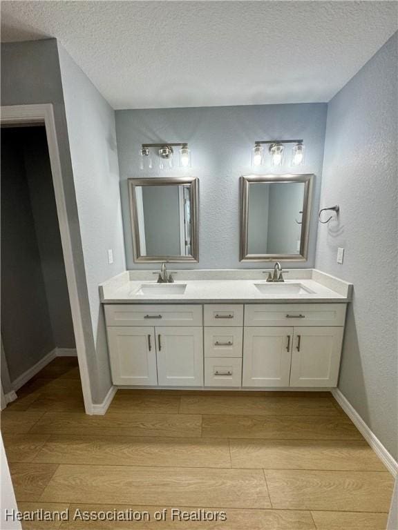 bathroom with a textured ceiling, hardwood / wood-style floors, and vanity