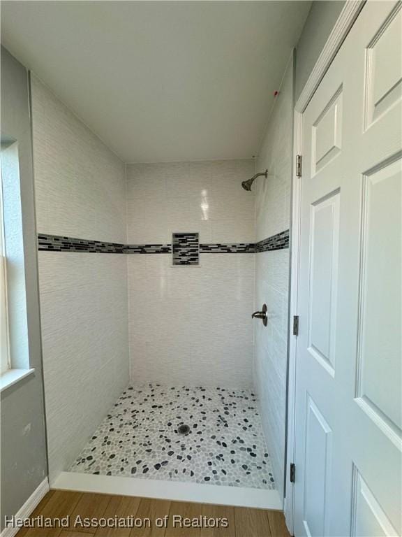 bathroom featuring hardwood / wood-style floors and a tile shower