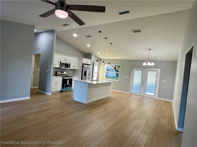 kitchen featuring pendant lighting, appliances with stainless steel finishes, white cabinetry, an island with sink, and high vaulted ceiling