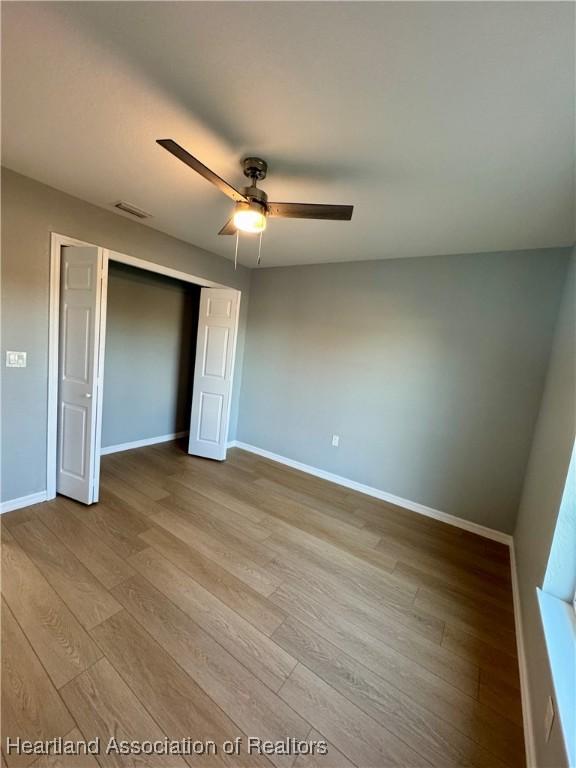 unfurnished bedroom with ceiling fan, light hardwood / wood-style flooring, and a closet