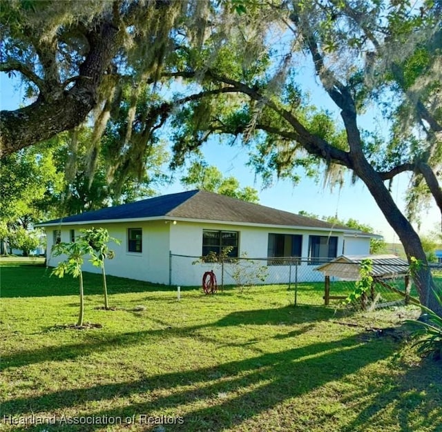 315 Sirena Dr, Lake Placid, FL 33852 - back of house featuring stucco siding, a yard, and fence
