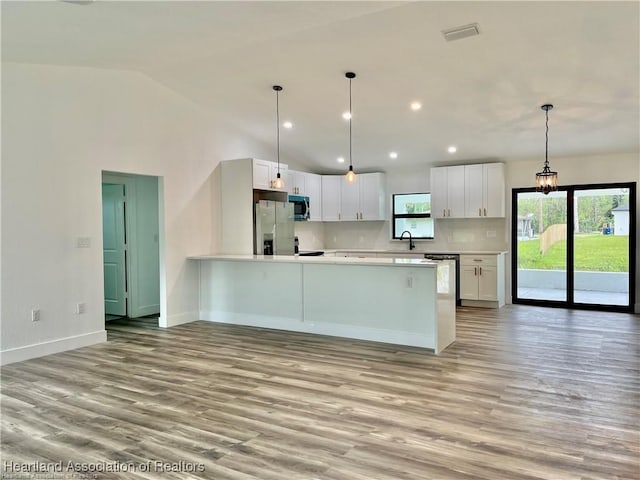 kitchen featuring stainless steel appliances, light countertops, white cabinets, and hanging light fixtures