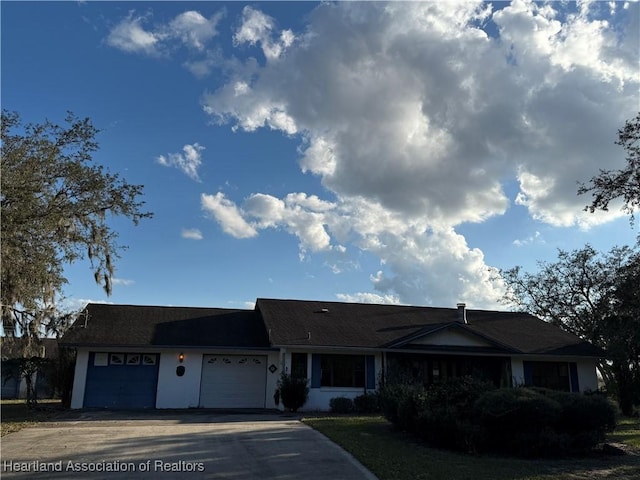 single story home featuring concrete driveway, an attached garage, and stucco siding