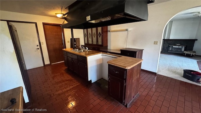 kitchen with arched walkways, extractor fan, butcher block countertops, a sink, and a kitchen island