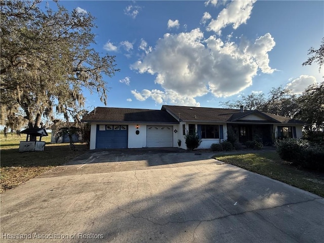 single story home featuring a garage, driveway, and stucco siding