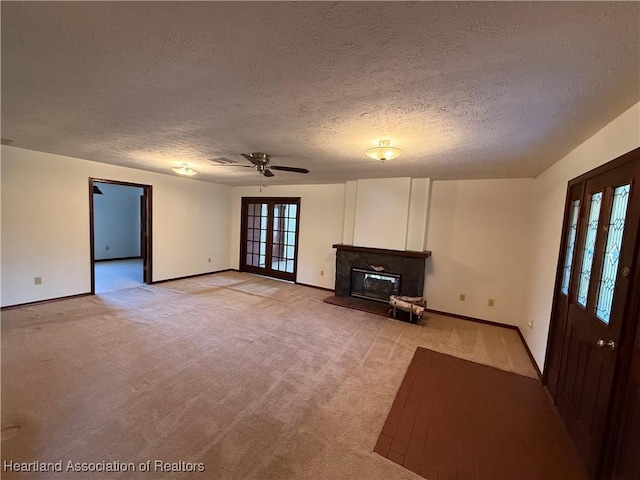 unfurnished living room featuring light carpet, baseboards, a glass covered fireplace, and french doors