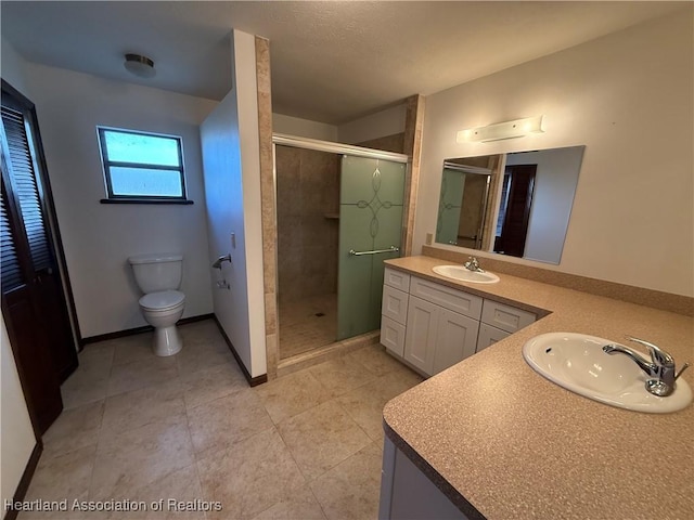 bathroom with double vanity, a stall shower, a sink, and toilet