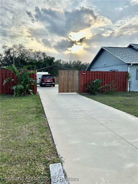 property exterior at dusk with a carport and a lawn