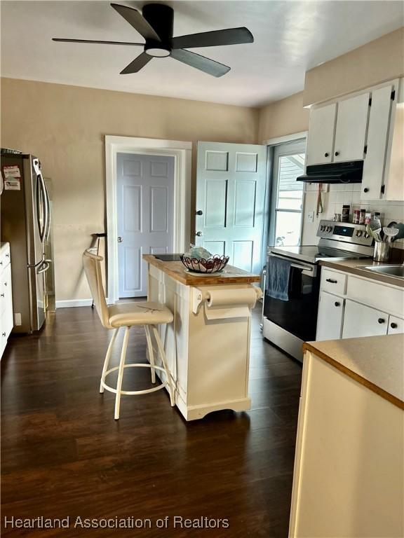 kitchen featuring dark hardwood / wood-style floors, white cabinetry, a breakfast bar, and appliances with stainless steel finishes