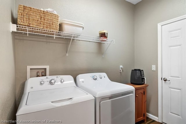 clothes washing area with separate washer and dryer and cabinets