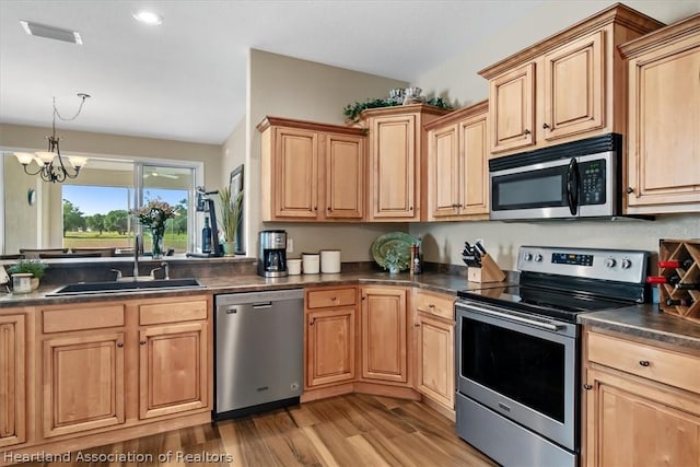 kitchen with a chandelier, sink, stainless steel appliances, and light hardwood / wood-style floors