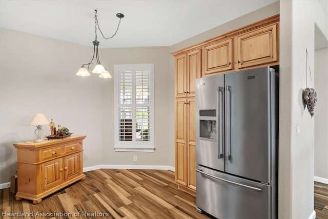 kitchen featuring light brown cabinets, stainless steel refrigerator with ice dispenser, pendant lighting, a chandelier, and wood-type flooring