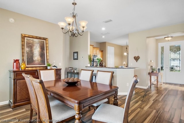 dining area with wood-type flooring and an inviting chandelier