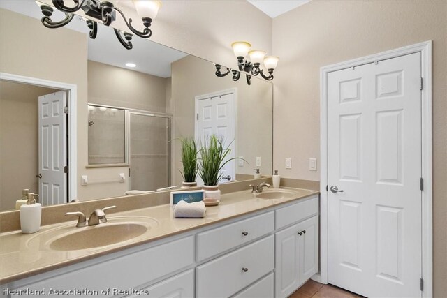 bathroom with a chandelier, vanity, tile patterned floors, and an enclosed shower