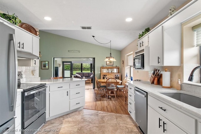 kitchen with light countertops, appliances with stainless steel finishes, hanging light fixtures, and white cabinetry