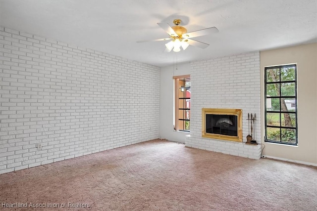 unfurnished living room with carpet flooring, ceiling fan, brick wall, and a brick fireplace