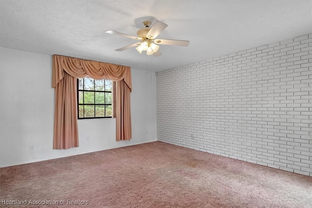 carpeted spare room featuring ceiling fan, a textured ceiling, and brick wall