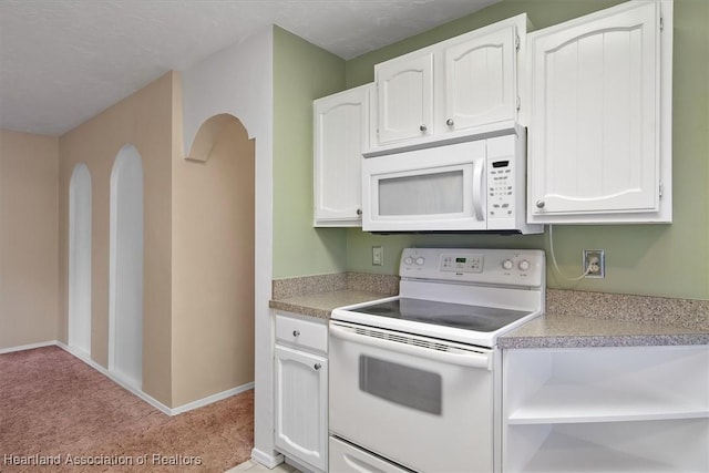 kitchen featuring a textured ceiling, white cabinetry, light colored carpet, and white appliances