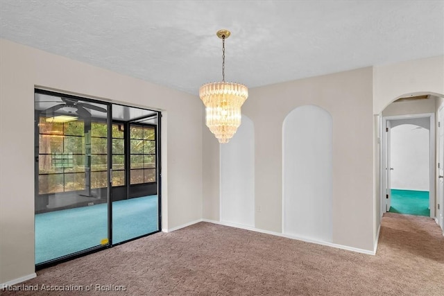 carpeted empty room featuring a chandelier and a textured ceiling