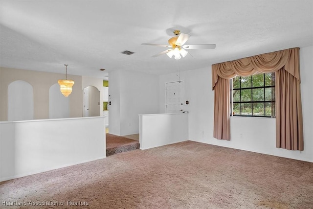 empty room featuring carpet floors and ceiling fan with notable chandelier