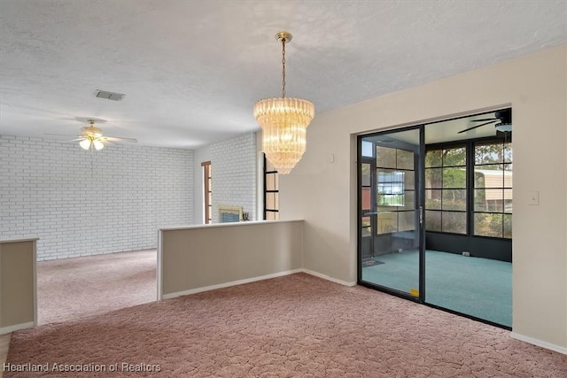 spare room with carpet, brick wall, and ceiling fan with notable chandelier