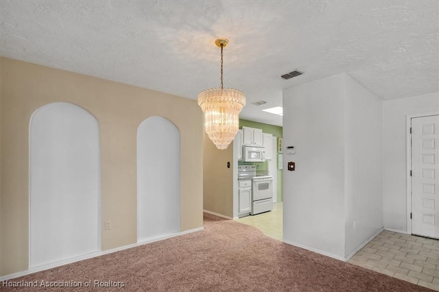 carpeted empty room featuring a textured ceiling and an inviting chandelier