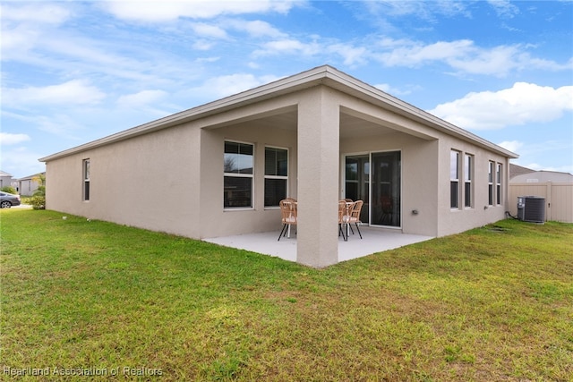 rear view of house featuring cooling unit, fence, a lawn, stucco siding, and a patio area