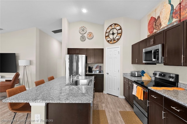 kitchen featuring visible vents, light wood-style flooring, appliances with stainless steel finishes, a sink, and a kitchen bar