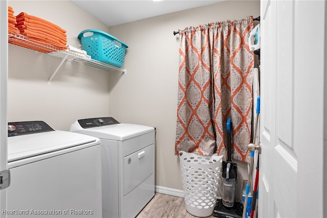 clothes washing area with laundry area, washing machine and dryer, baseboards, and light wood-style floors