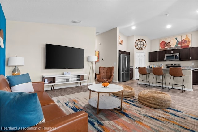 living area with light wood finished floors, baseboards, visible vents, and recessed lighting