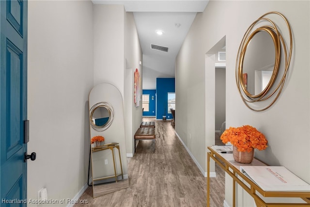 hallway featuring visible vents, baseboards, and wood finished floors