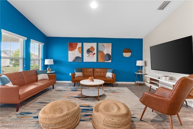 living room with lofted ceiling, baseboards, visible vents, and wood finished floors