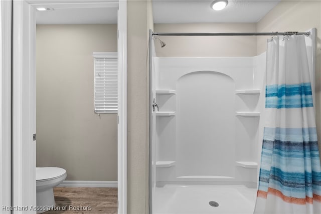 bathroom featuring curtained shower, wood finished floors, toilet, and baseboards