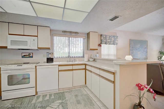 kitchen with white appliances, sink, a textured ceiling, light tile patterned flooring, and kitchen peninsula