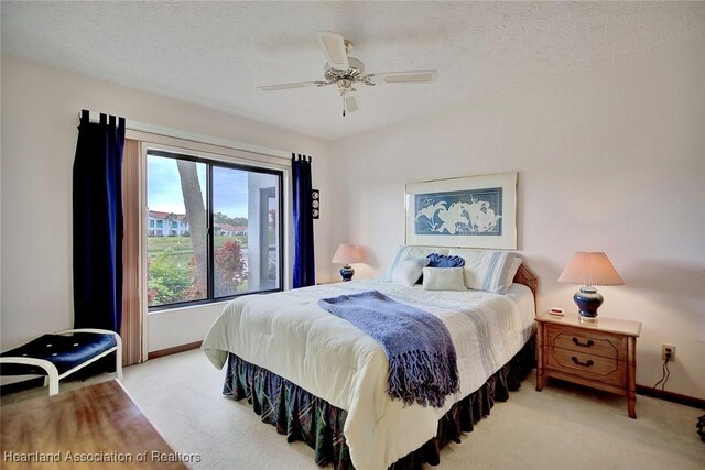 carpeted bedroom featuring ceiling fan and a textured ceiling