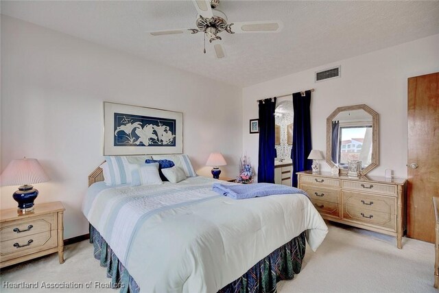 carpeted bedroom featuring ceiling fan and a textured ceiling