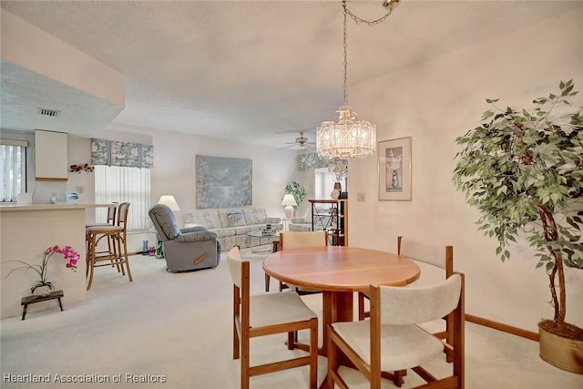 dining room with a textured ceiling, light colored carpet, and ceiling fan