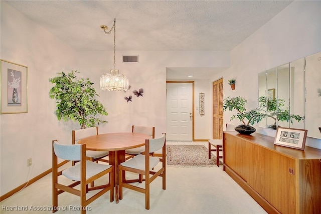 dining area with a textured ceiling, light carpet, and a chandelier