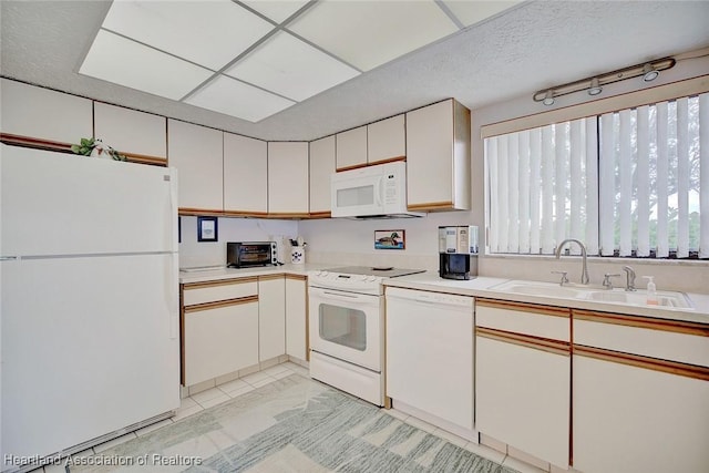 kitchen with white cabinetry, white appliances, and sink