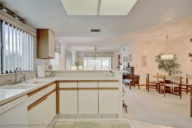 kitchen with light carpet, kitchen peninsula, a textured ceiling, sink, and dishwasher