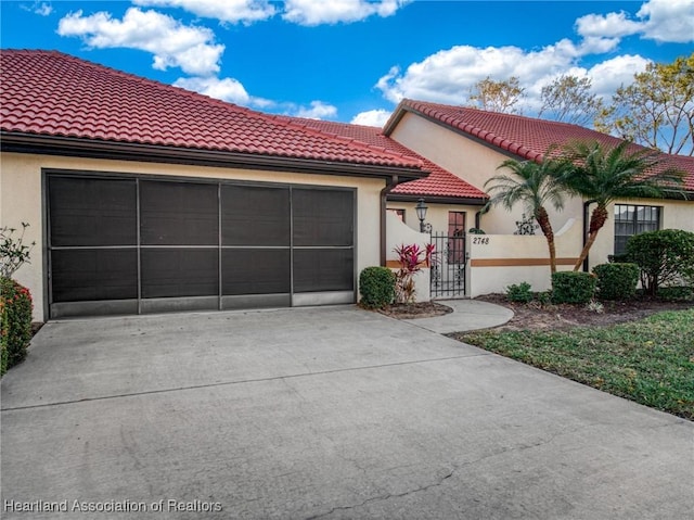 mediterranean / spanish home featuring concrete driveway, an attached garage, a tiled roof, and stucco siding