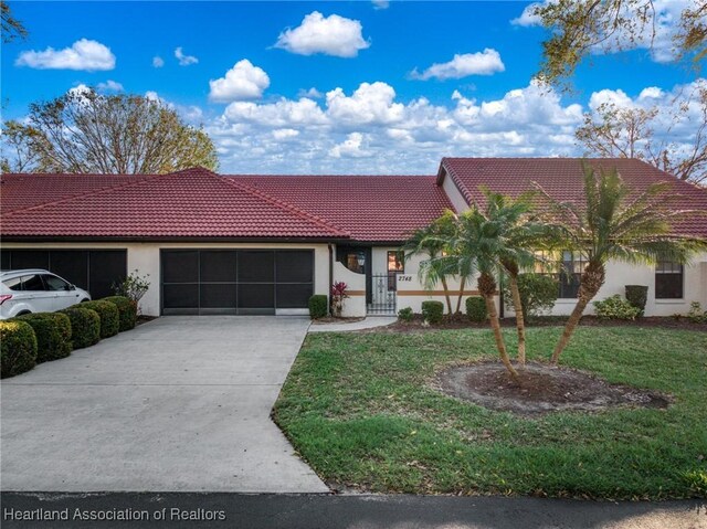 view of front of home featuring driveway, a tile roof, an attached garage, a front yard, and stucco siding