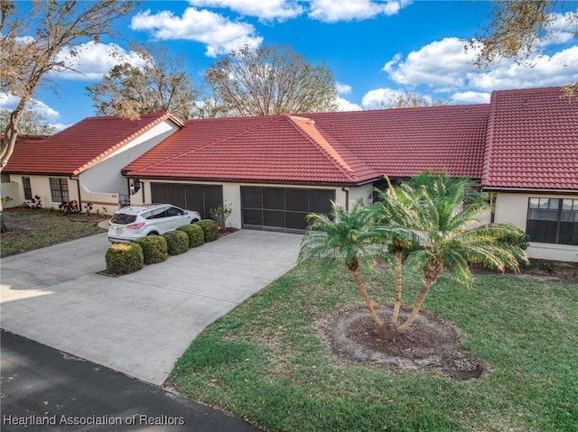 mediterranean / spanish-style home with a garage, a tiled roof, concrete driveway, stucco siding, and a front yard