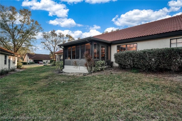 rear view of house with a lawn and a sunroom