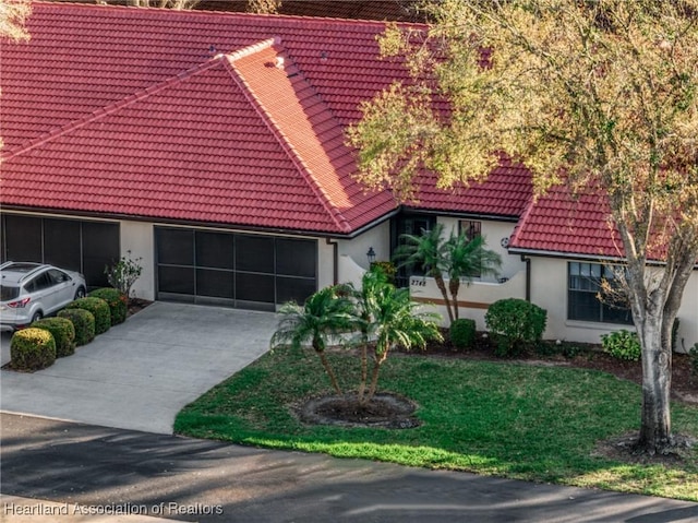 mediterranean / spanish house with a garage, concrete driveway, a tiled roof, and stucco siding