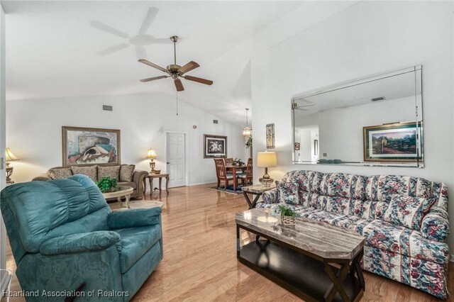 living area featuring lofted ceiling, light wood-type flooring, and a ceiling fan