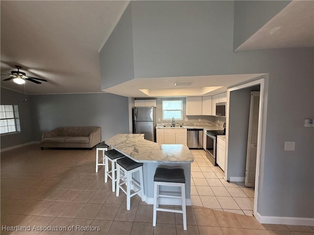 4329 Elson Ave, Sebring, FL 33875 - kitchen featuring appliances with stainless steel finishes, a kitchen bar, baseboards, light tile patterned flooring, and white cabinets