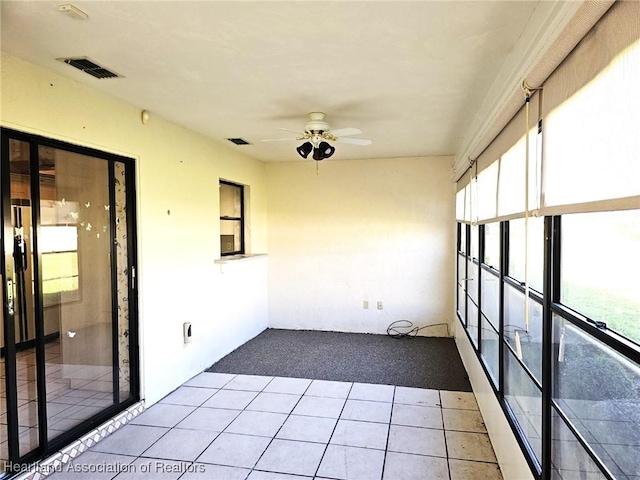 unfurnished sunroom featuring ceiling fan and plenty of natural light