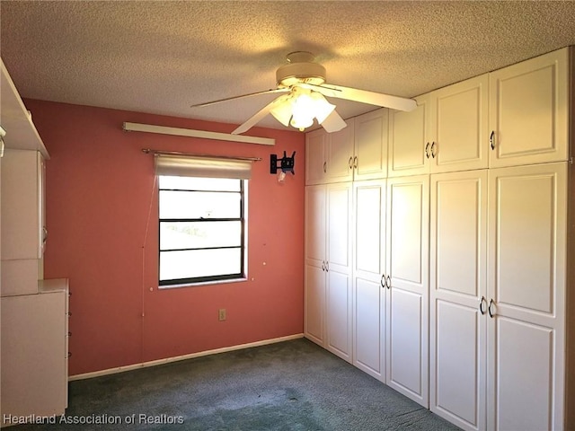 unfurnished bedroom featuring ceiling fan, dark carpet, a textured ceiling, and a closet