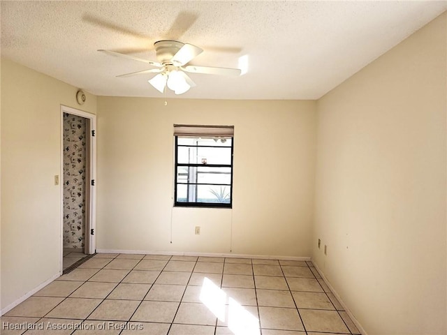 spare room with ceiling fan, light tile patterned flooring, and a textured ceiling